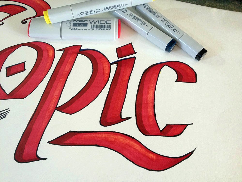 Copic Stifte und Wide Marker liegen auf einem handgezeichneten roten Copic-Schriftzug auf hellem Papier.