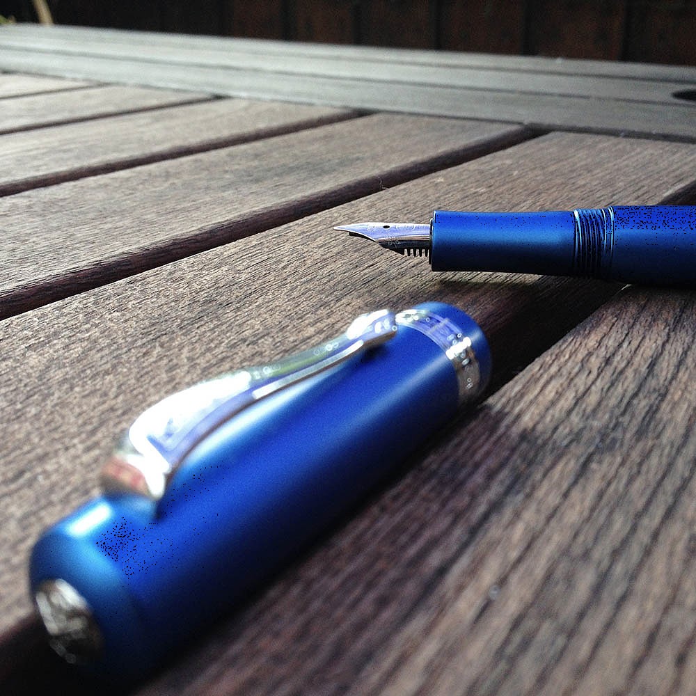 Blauer Kaweco Füllhalter auf Holztisch im Außenbereich